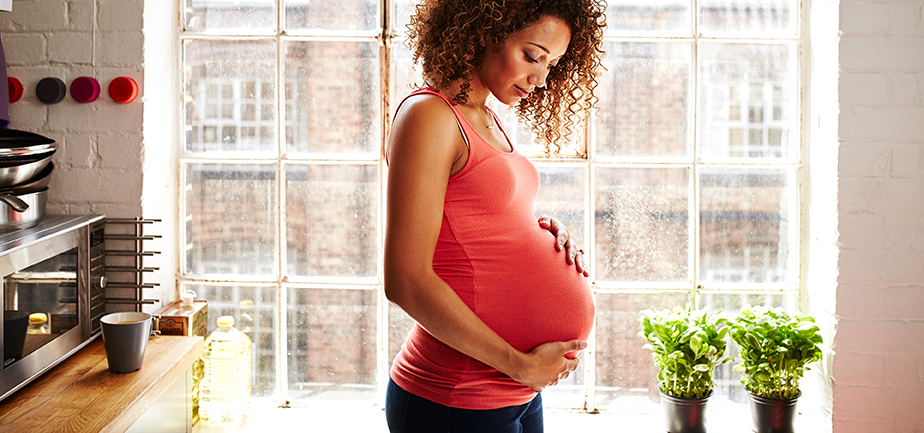 Pregnant woman in house touching belly