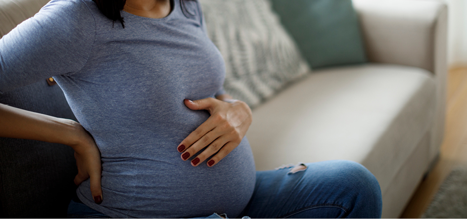 pregnant woman holding her back and belly
