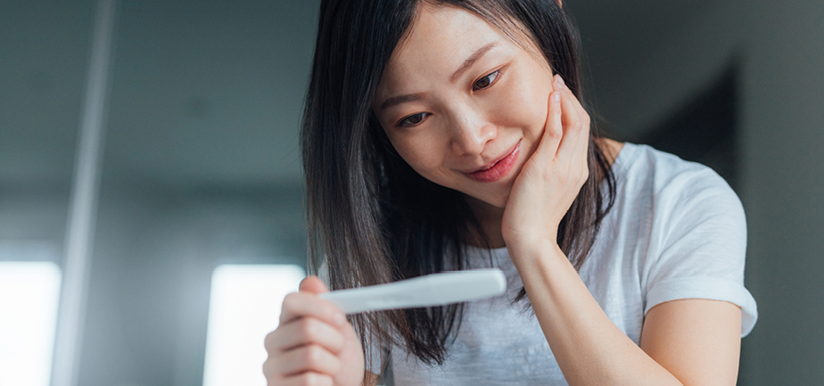 woman happy looking at pregnancy test