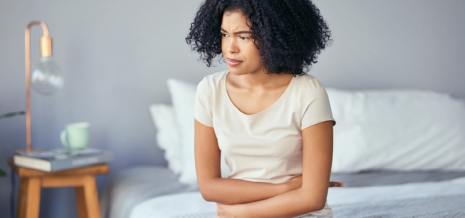 woman in bedroom holding her stomach