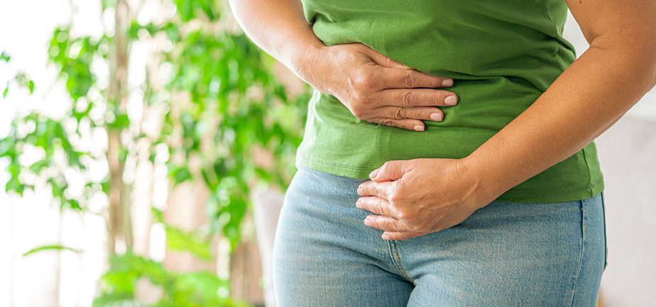 Woman touching her stomach experiencing abdominal pain at home