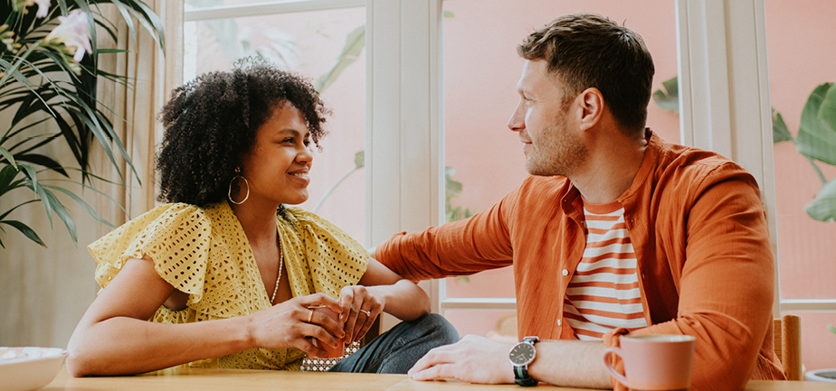 A couple in a long-term relationship look happy and loving as they chat at a dining table.