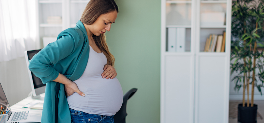 Pregnant businesswoman with stomach pain at workplace