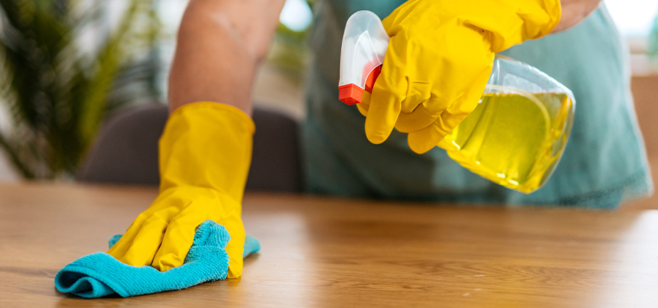 Senior woman wiping the dining room table at home.