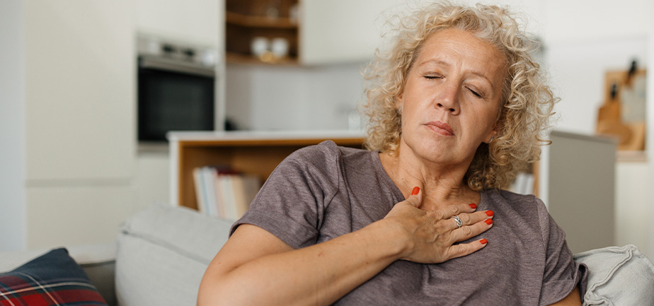 Mid adult woman having chest pain in the sofa