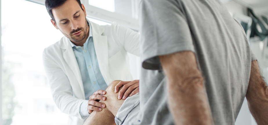 Senior man having his knee examined by a doctor. 