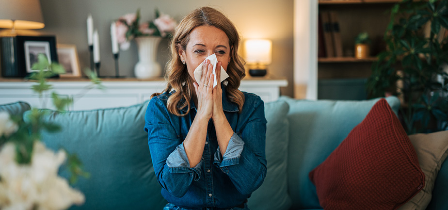 Woman blowing nose feeling unwell at home