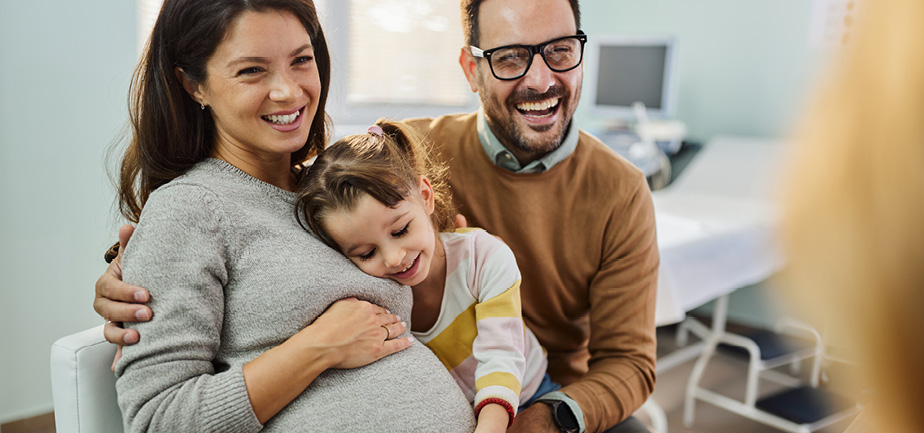 Happy pregnant family having an appointment at gynecologists' office.