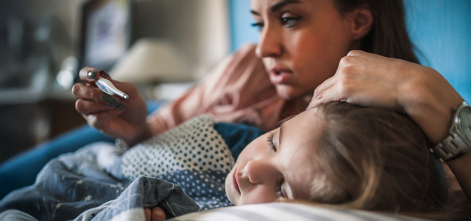 Parent measuring temperature on sick child