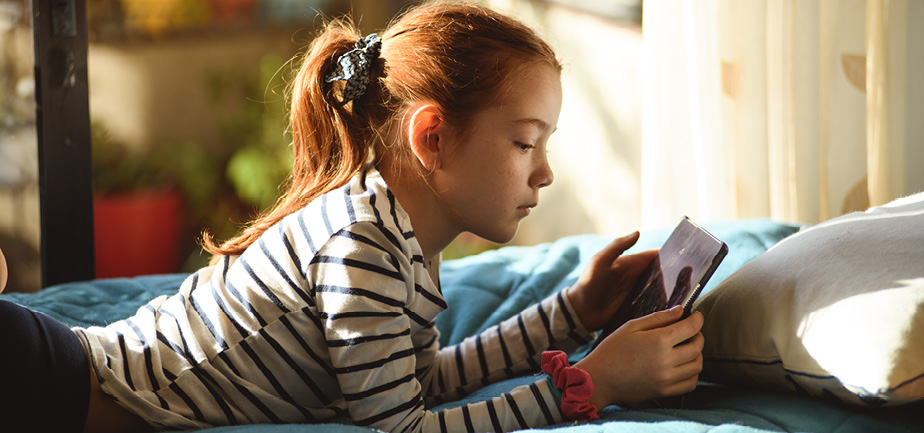 Elementary aged girl concentrated on playing with tablet