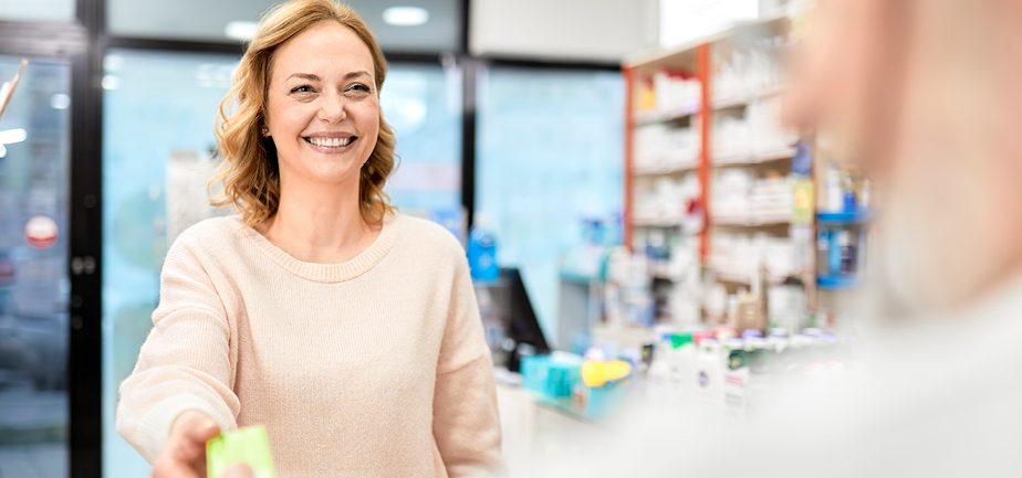 Smiling customer receiving medicine from pharmacist at pharmacy store