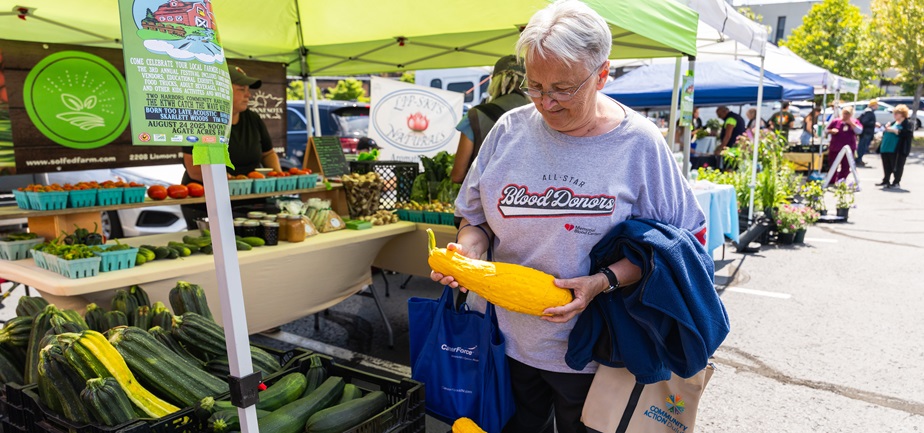 Cheryl Olson inspected a squash at the farmers market in August.