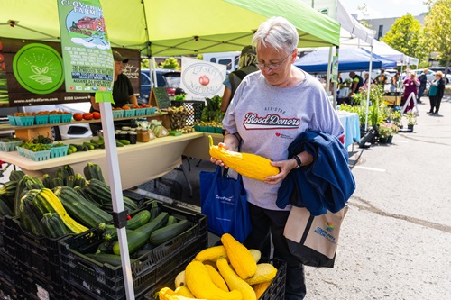 Cheryl Olson inspected a squash at the farmers market in August.