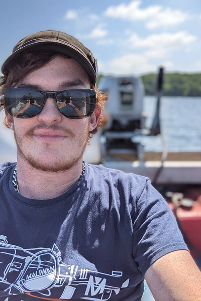 man with a hat and sunglasses smiling at camera