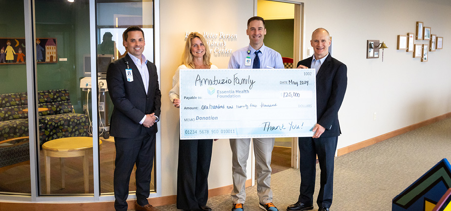 four people standing with a big check