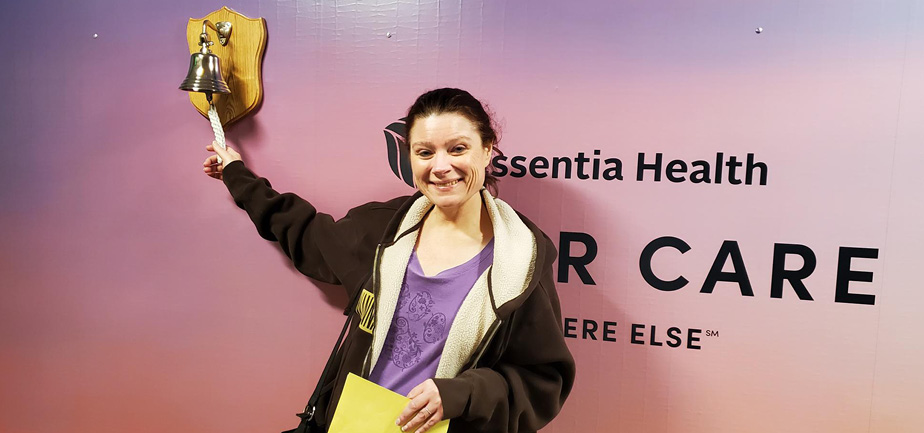 woman smiling and ringing a bell at a cancer center