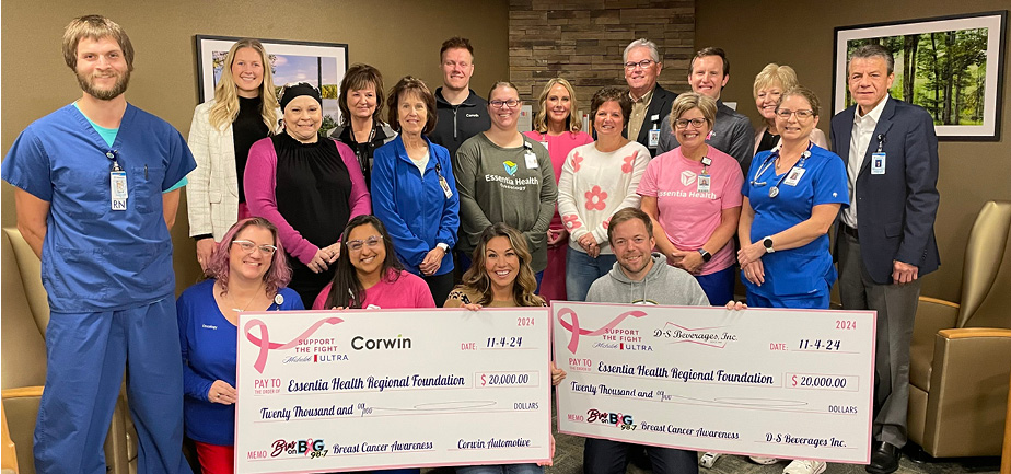 large group gathered together for a photo with two big fundraiser checks