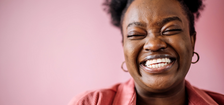 black woman smiling with pink background