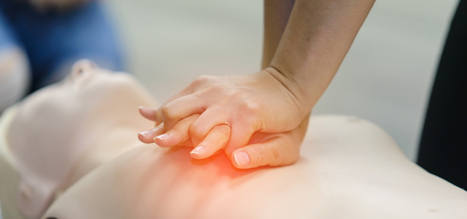 hands performing CPR on example dummy