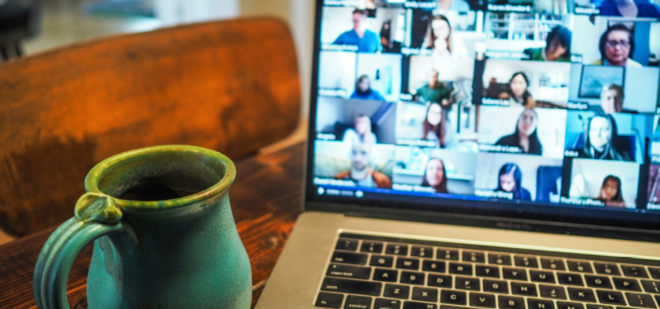 Coffee mug in front of a laptop with a virtual meeting