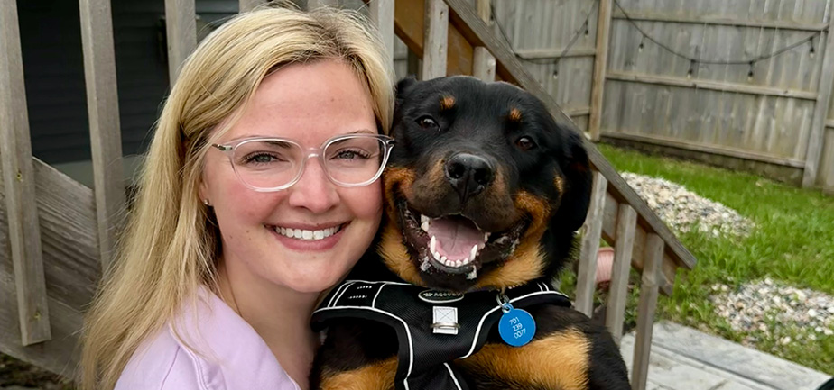 woman with glasses smiling and holding dog