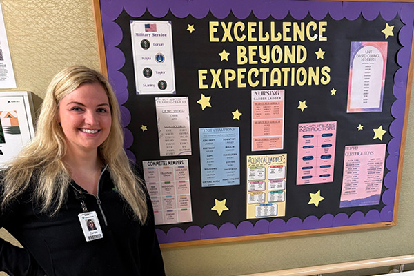 woman smiling and standing in front of a bulletin board