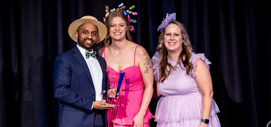 man holding an award and smiling alongside two women