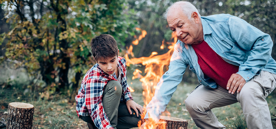 older man and his grandson tending to a fire