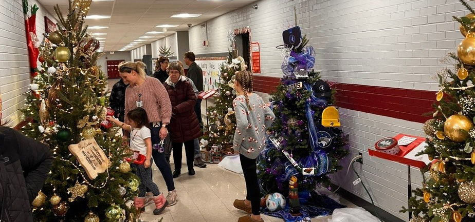 people looking at decorated trees in a hallway