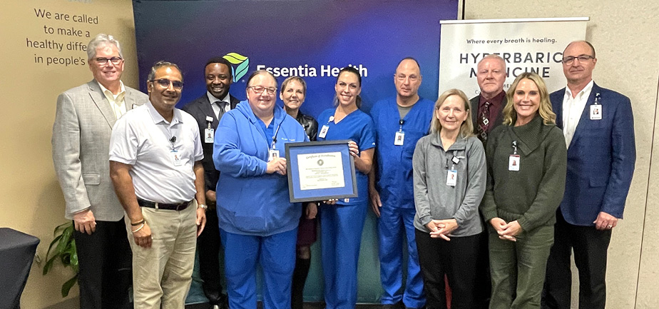 Large group of people standing together, smiling and holding a framed certificate.