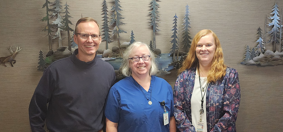 one male provider standing with two female providers, smiling in a group