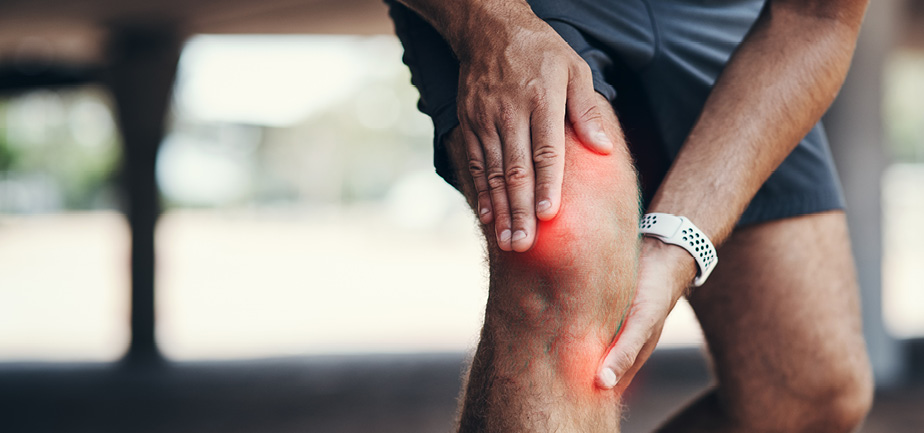 unidentified man pressing his hands around his right knee