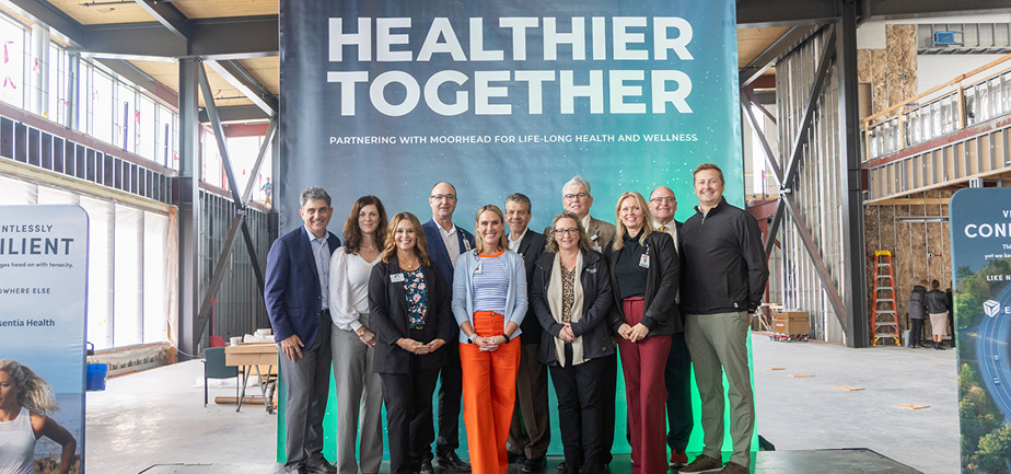 large group of people standing in front of a sign that says 'healthier together'