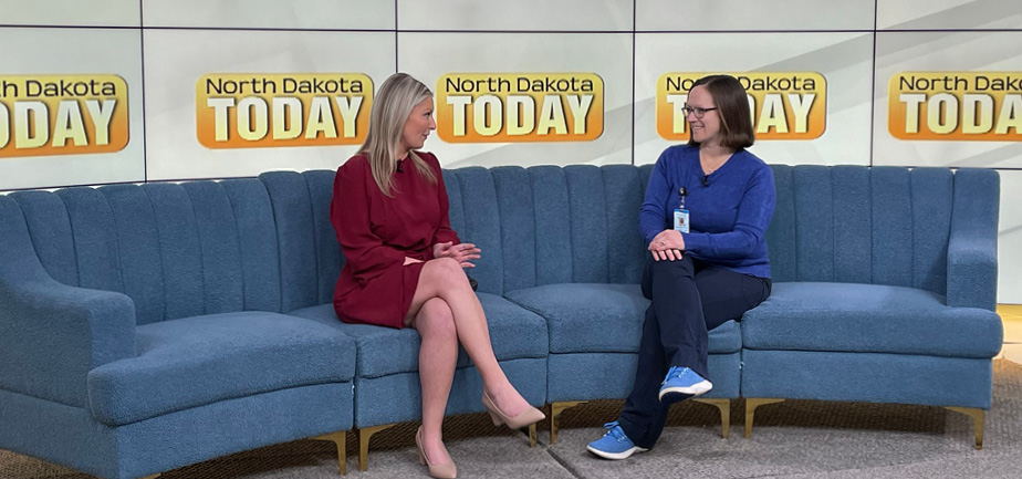 two women sitting on blue couch in newsroom