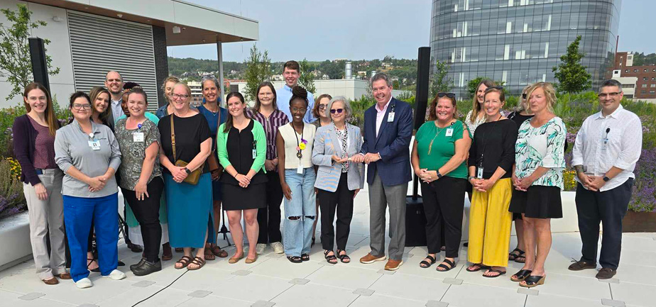 large group standing with an award on a rooftop