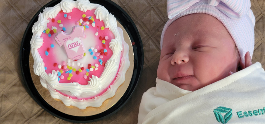 Newborn baby girl next to a cake