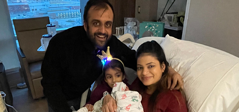 Mother, father and young daughter holding newborn baby boy