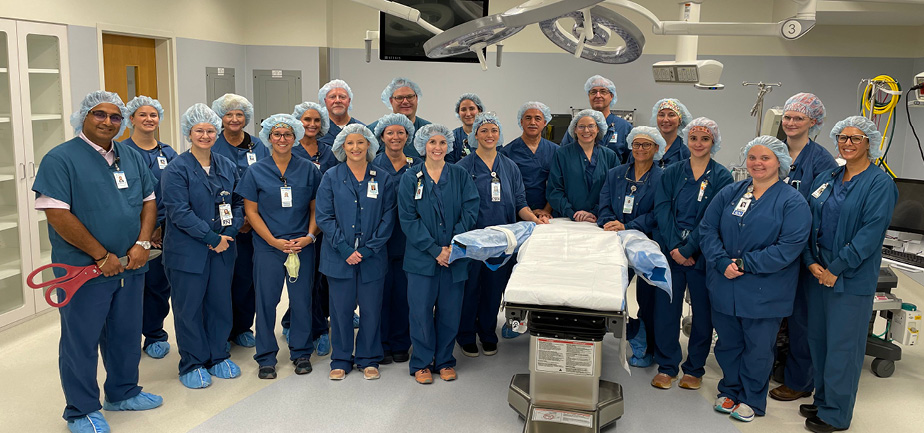 large group of people in scrubs in an operating room