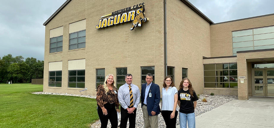 group of five people standing outside of a school