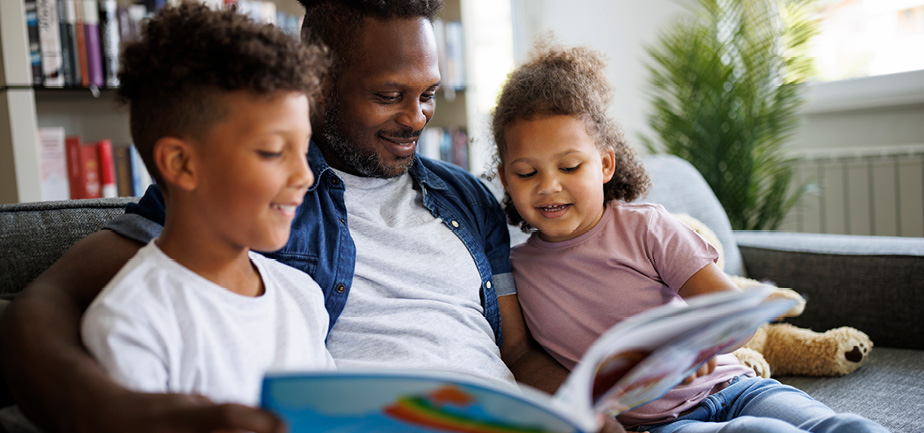 African American dad reading with his son and daughter