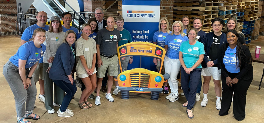 large group of adults gathered around school bus cut out for a photo