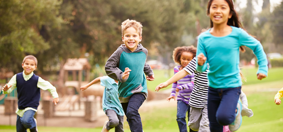 several children running outside in the grass