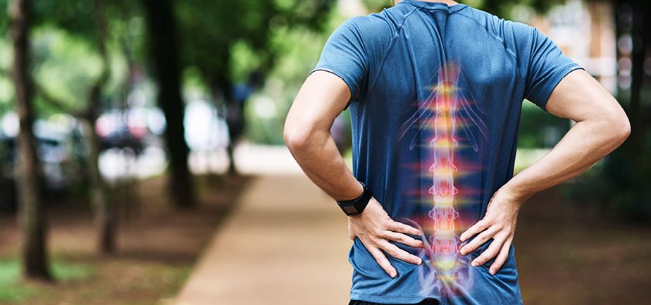 man in blue shirt holding his lower back due to pain