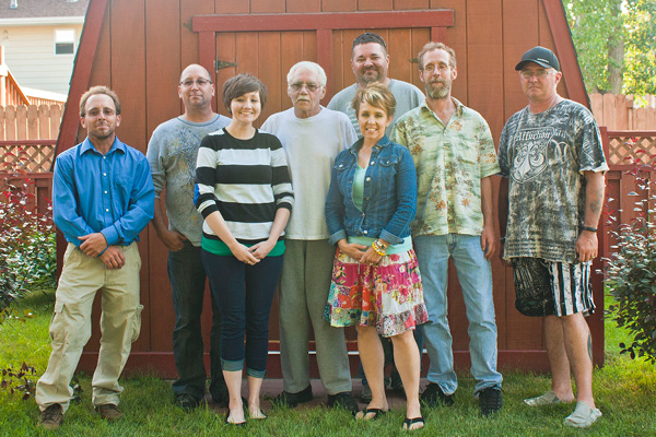 group of eight people standing together for a photo outside