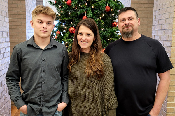 man standing with his wife and son in front of a tree