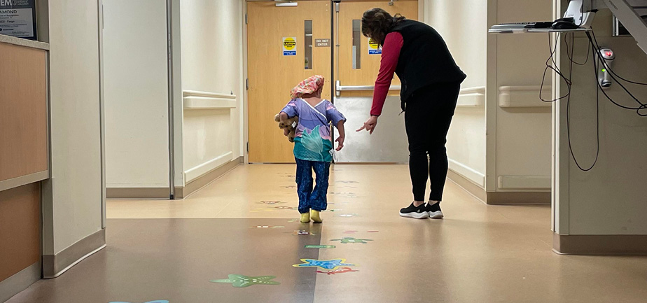 woman walking down a hallway with a young patient