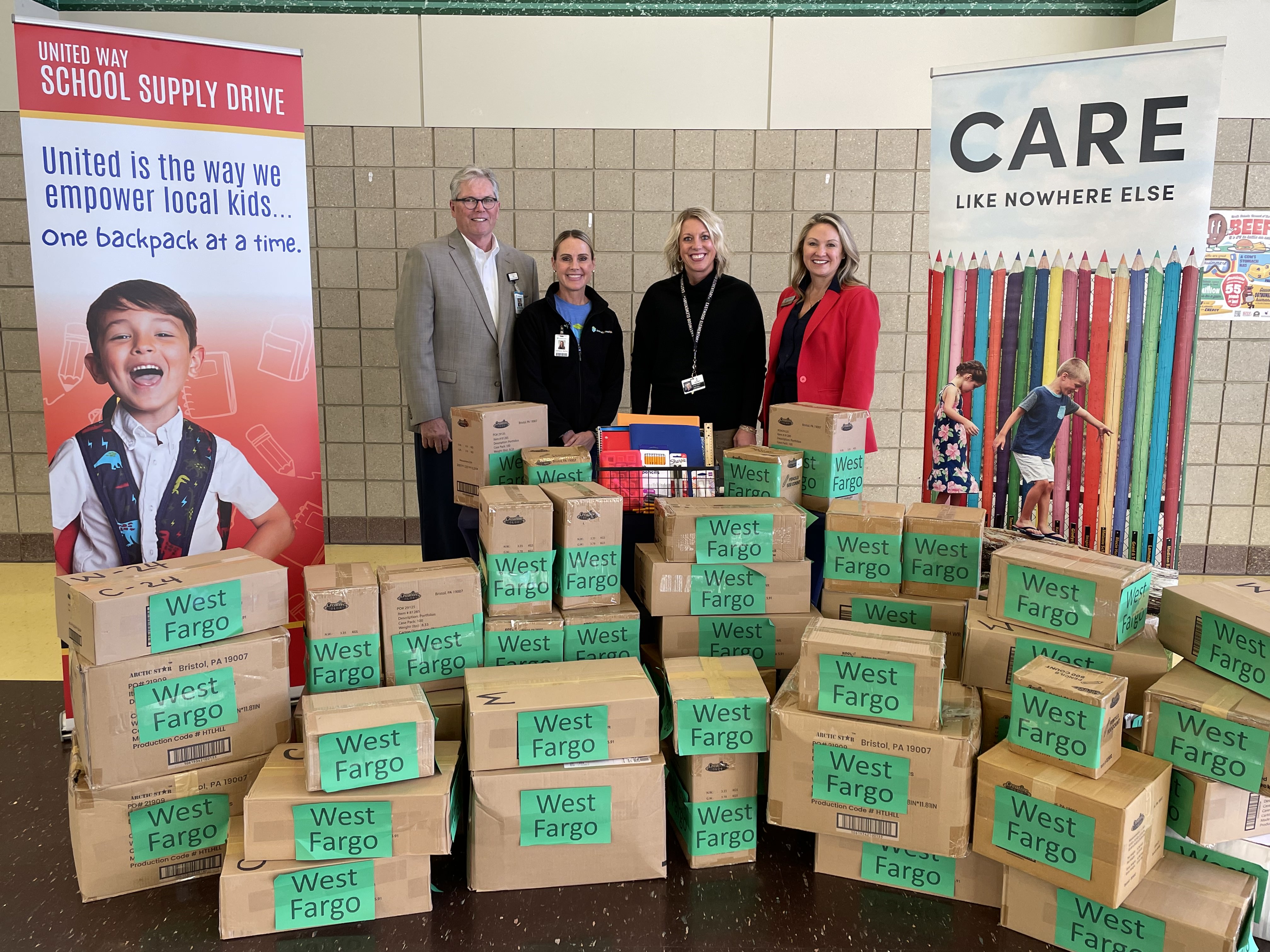 four adults standing behind many brown package boxes with West Fargo labels on them