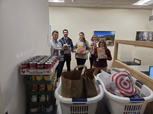 People holding boxes of cereals and standing behind several baskets of foos stuff