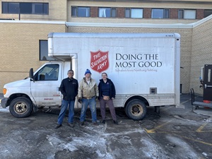 two men and a woman standing by a white box truck while smiling