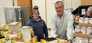 Two people standing behind a table displaying foodstuffs